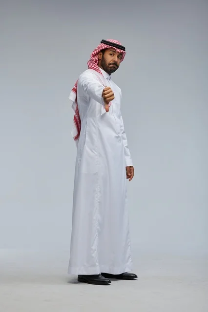 رجل سعودي بالزي التقليدي يشير بعلامة عدم الإعجاب
