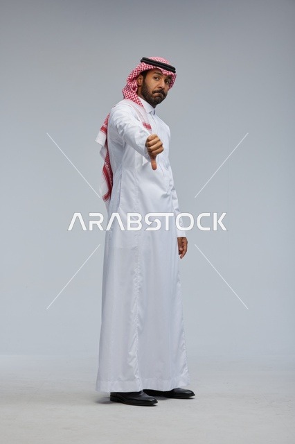 رجل سعودي بالزي التقليدي يشير بعلامة عدم الإعجاب