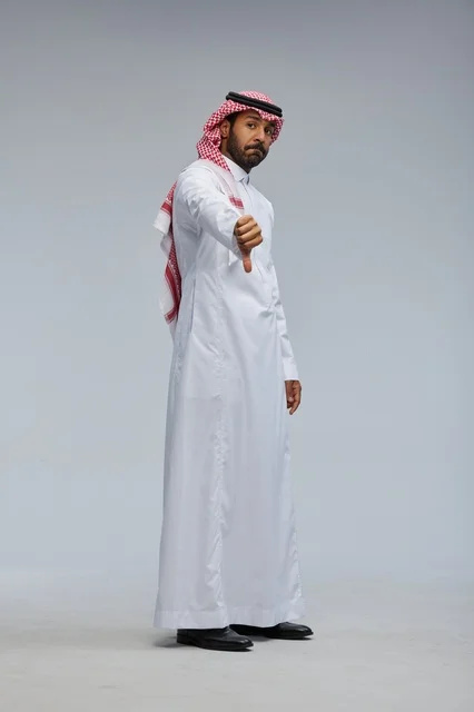 رجل سعودي بالزي التقليدي يشير بعلامة عدم الإعجاب