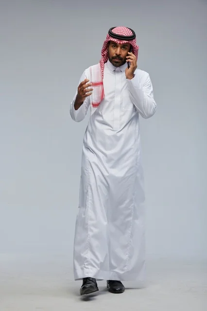 Saudi Man in Traditional Thobe Talking on Smartphone