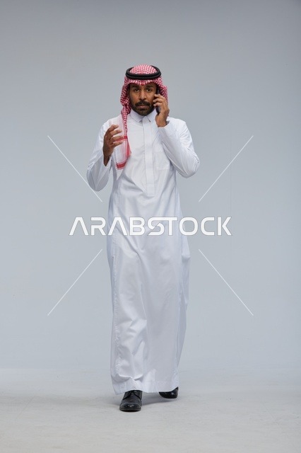 Saudi Man Talking on Smartphone on Grey Background