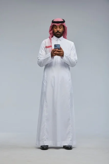 رجل سعودي يستخدم هاتف ذكي بالزي التقليدي