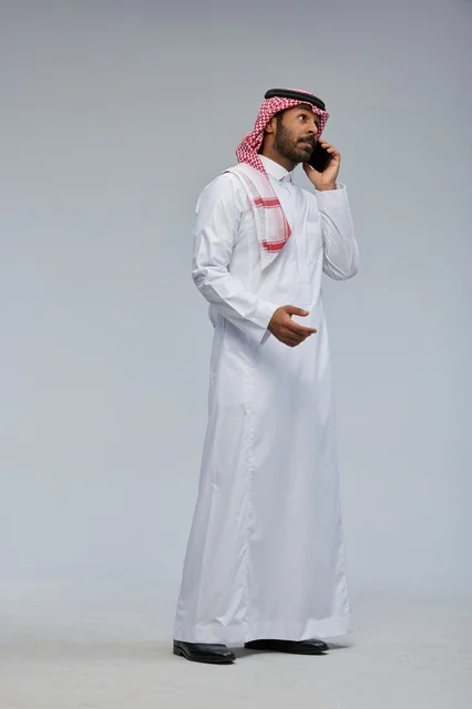 رجل سعودي بالزي التقليدي يتحدث بالهاتف الذكي