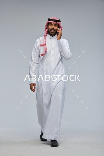 رجل سعودي يتحدث بالهاتف الذكي ويمشي في الاستوديو