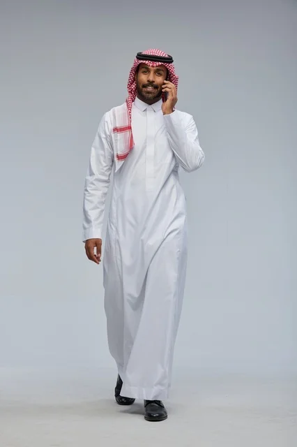 رجل سعودي يتحدث بالهاتف الذكي ويمشي في الاستوديو
