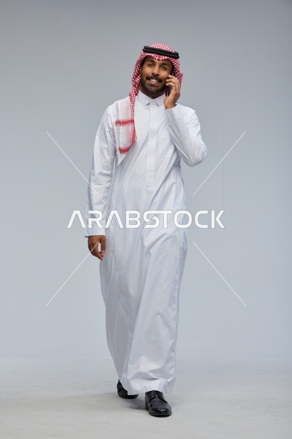 رجل سعودي بالثوب التقليدي يتحدث عبر الهاتف الذكي