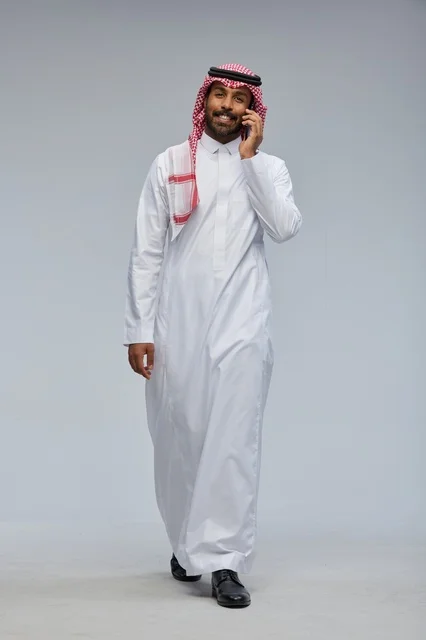 رجل سعودي بالثوب التقليدي يتحدث عبر الهاتف الذكي