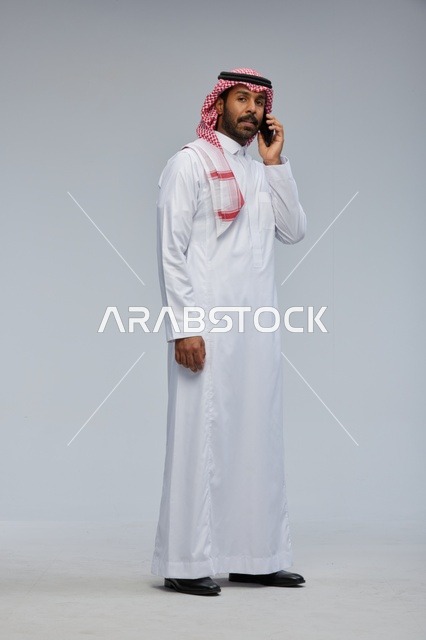رجل سعودي يتحدث بالهاتف الذكي بالزي التقليدي