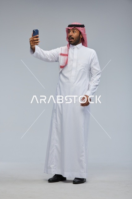رجل سعودي يلتقط سيلفي بالهاتف في الاستوديو