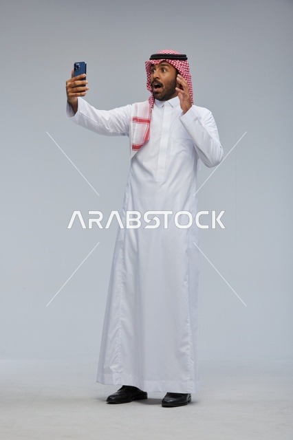 Saudi man taking selfie with smartphone and interacting with the camera