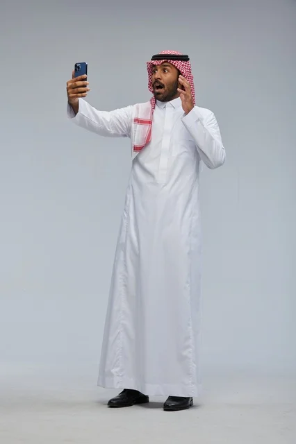 Saudi man taking selfie with smartphone and interacting with the camera Saudi man taking selfie with smartphone and interacting with the camera