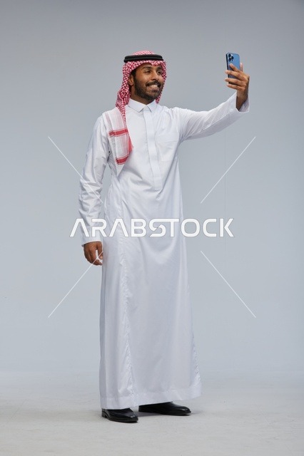 Saudi Man in Traditional Thobe Taking Smartphone Selfie
