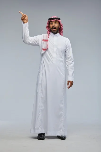 رجل سعودي بالزي التقليدي يشير بإصبعه بتعبير متفاجئ