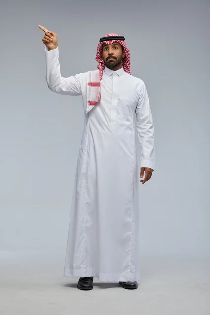 رجل سعودي بالزي التقليدي يشير للأعلى في استوديو