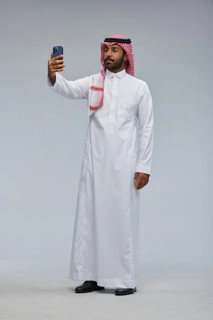 رجل سعودي بالثوب التقليدي يلتقط صورة سيلفي بالجوال