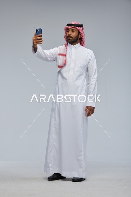 Saudi Man in Thobe Taking Selfie on Smartphone