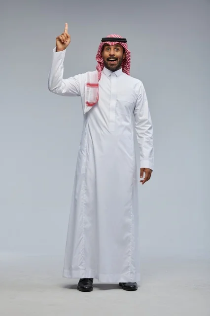 رجل سعودي بالزي التقليدي يشير للأعلى في استوديو