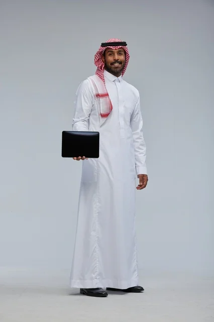 رجل سعودي بالزي التقليدي يحمل جهازاً لوحياً