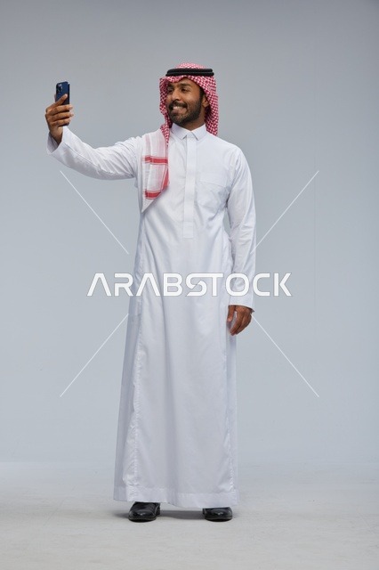 Saudi Man in Traditional Thobe Taking Smartphone Selfie