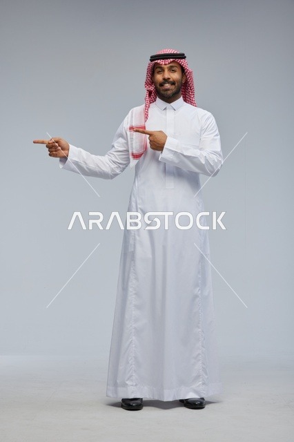رجل سعودي بالزي التقليدي يشير إلى الجانب