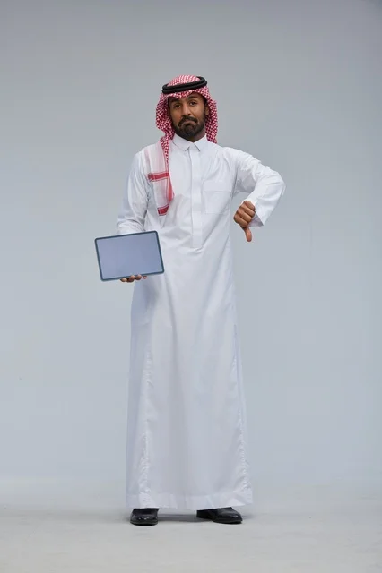 رجل سعودي مع جهاز لوحي وإيماءة الإبهام للأسفل