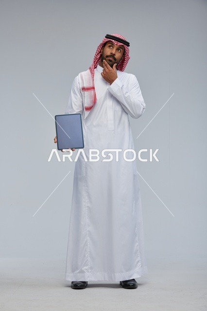Saudi Man Holding Blank Tablet Thinking Studio Shot