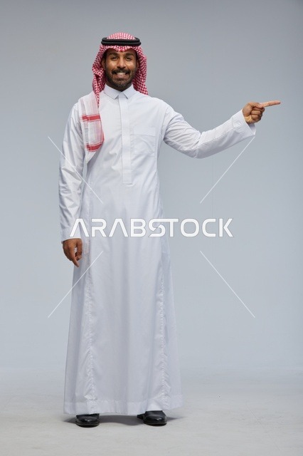 Saudi Man in Traditional Thobe Pointing on Grey Background