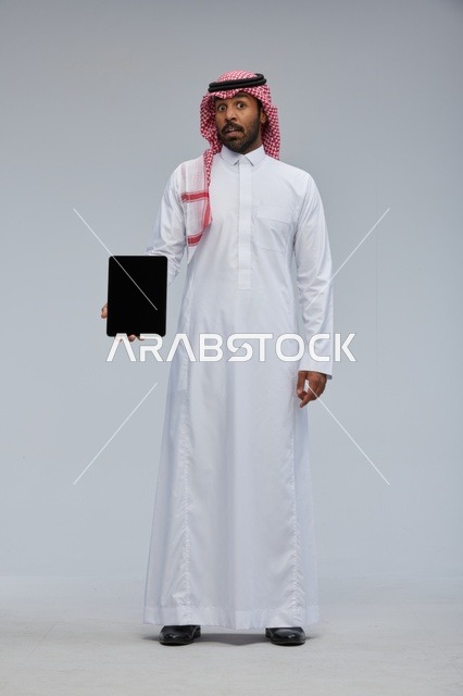 Saudi Man Holding Digital Tablet Against Studio Background