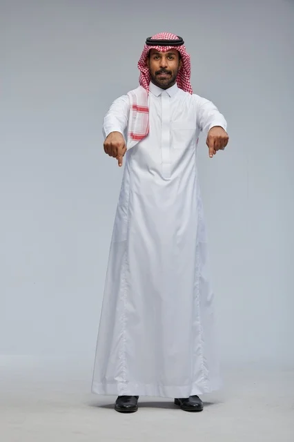 رجل سعودي بالزي التقليدي يشير إلى الأسفل