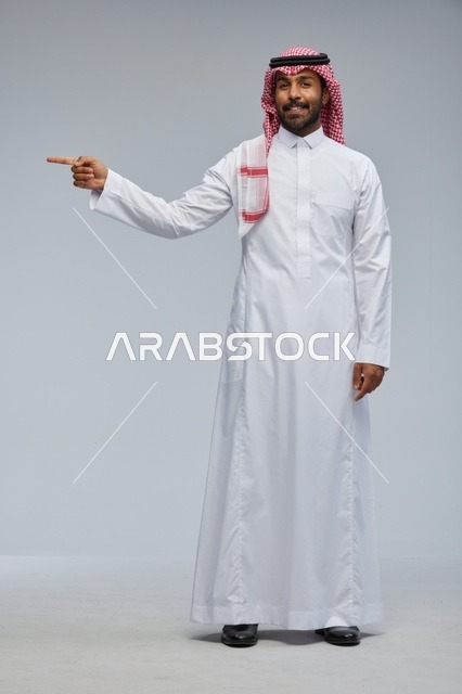 Smiling Saudi Man in Traditional Dress Pointing to Side