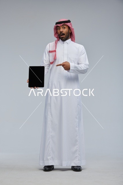 Saudi Man Holding Tablet with Surprised Expression