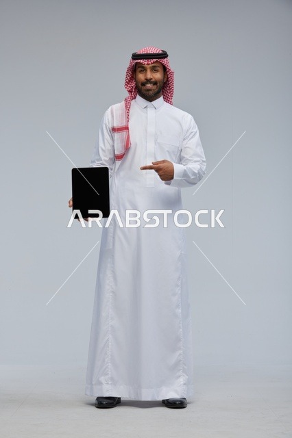 رجل سعودي يشير إلى شاشة جهاز لوحي في الاستوديو