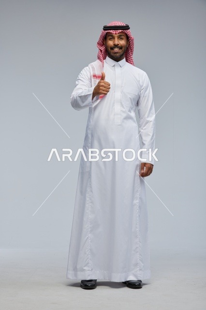 رجل سعودي بالزي التقليدي يبتسم ويشير بعلامة الإعجاب