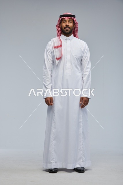 رجل سعودي بالزي التقليدي أمام خلفية رمادية