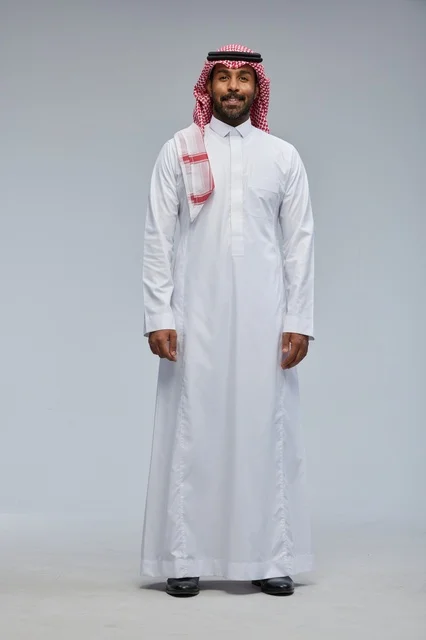 رجل سعودي بالزي التقليدي في استوديو مبتسم للكاميرا