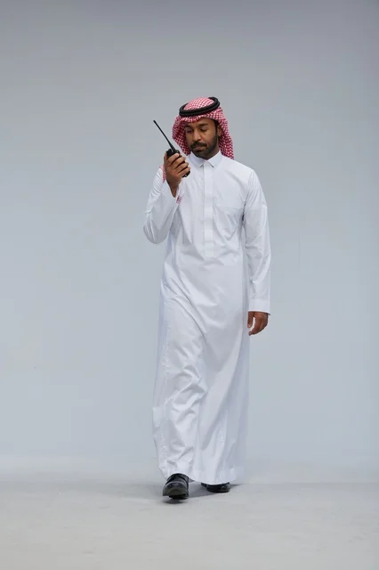 Saudi Man Using Walkie Talkie on Gray Background