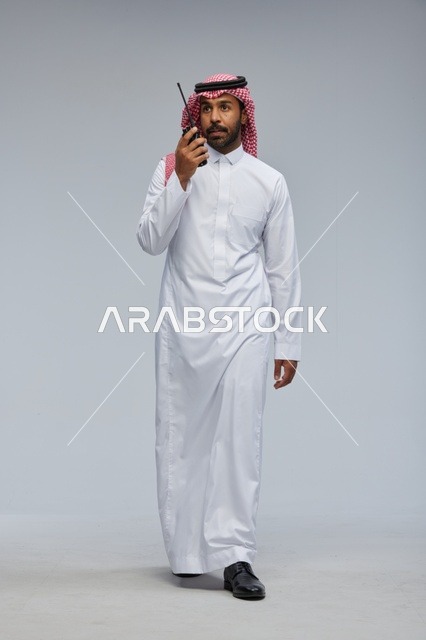 Saudi Man Using Walkie-Talkie in Traditional Thobe