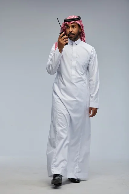 Saudi Man Using Handheld Walkie Talkie on Grey Background