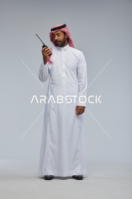 Saudi Man Using Walkie-Talkie in Traditional Thobe