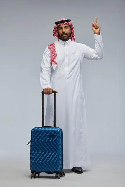 رجل سعودي بالزي التقليدي مع حقيبة سفر زرقاء