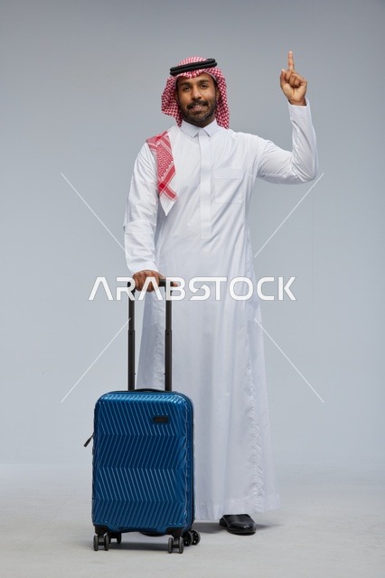 رجل سعودي بالزي التقليدي مع حقيبة سفر زرقاء