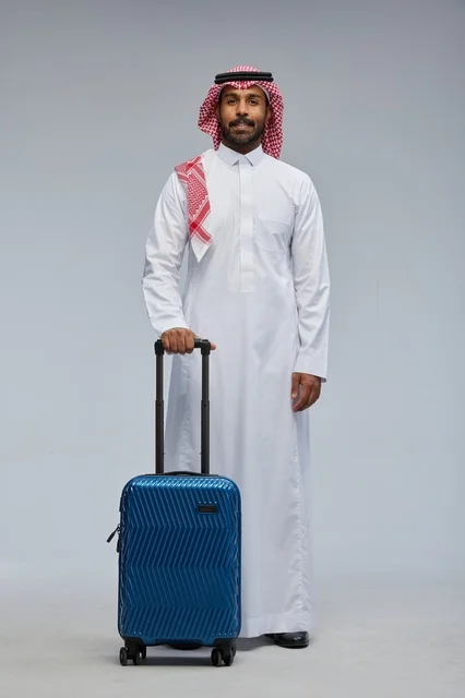 رجل سعودي بالزي التقليدي مع حقيبة سفر زرقاء