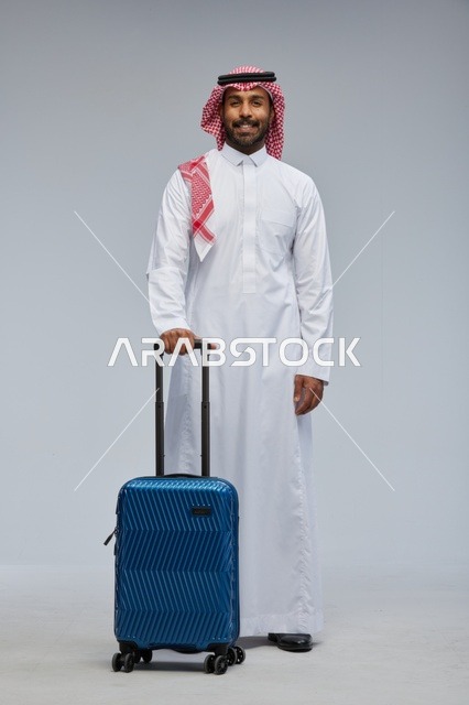 رجل سعودي يرتدي الزي التقليدي مع حقيبة سفر زرقاء