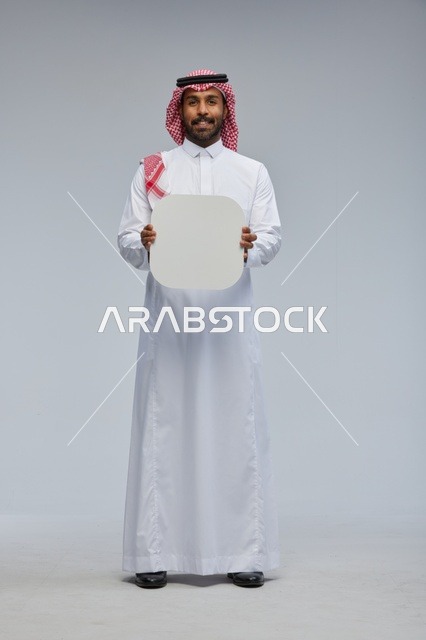 رجل سعودي مبتسم يحمل لوحة بيضاء فارغة في الاستوديو
