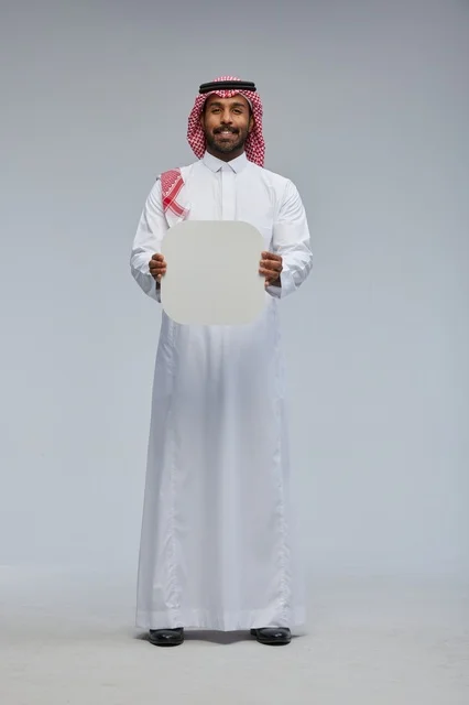 رجل سعودي مبتسم يحمل لوحة بيضاء فارغة في الاستوديو