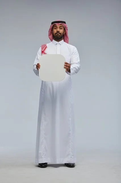 رجل سعودي بالزي التقليدي يحمل لوحة بيضاء فارغة