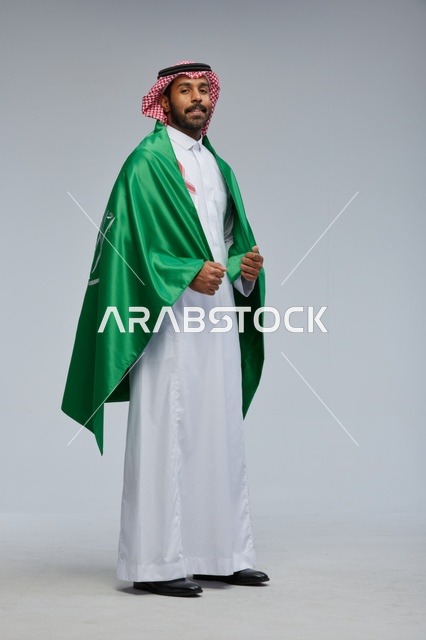 رجل سعودي يحمل علم المملكة بالزي التقليدي