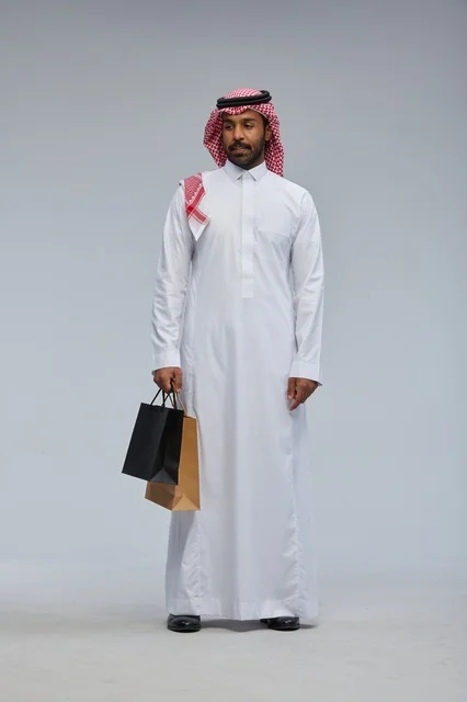 Saudi Man in Traditional Thobe Holding Shopping Bags