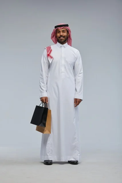رجل سعودي يحمل أكياس تسوق بالزي التقليدي