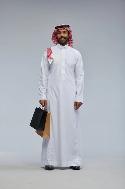 Saudi Man in Traditional Attire Holding Shopping Bags
